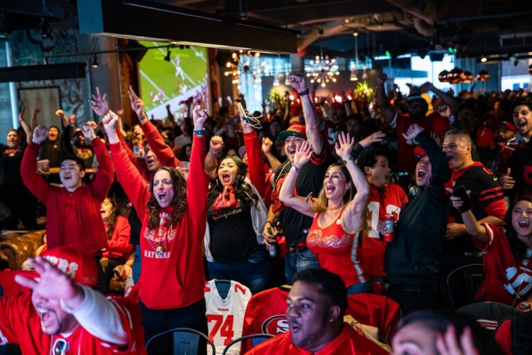 A crowd in a sports bar watching an event and cheering