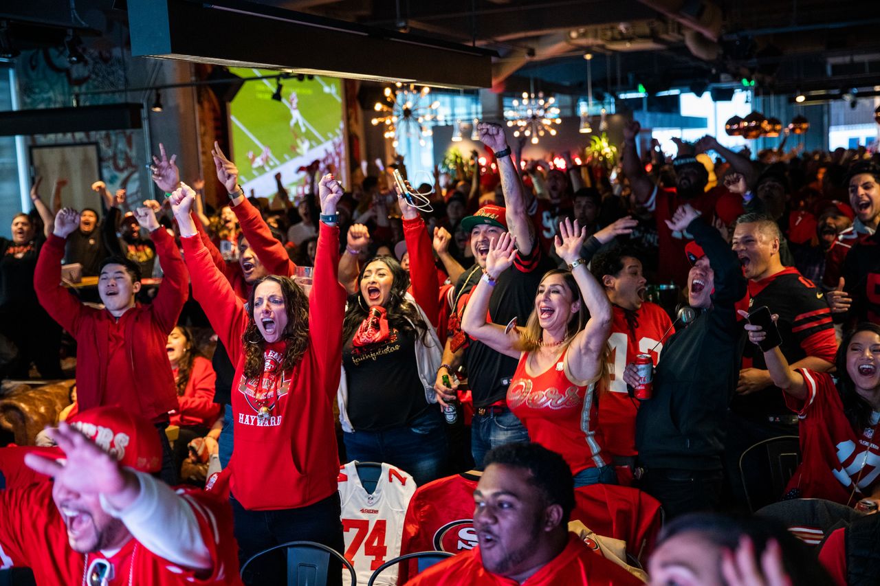 A crowd in a sports bar watching an event and cheering