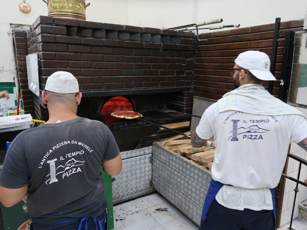 Chefs preparing pizza in wood-fired oven at Da Michele Naples