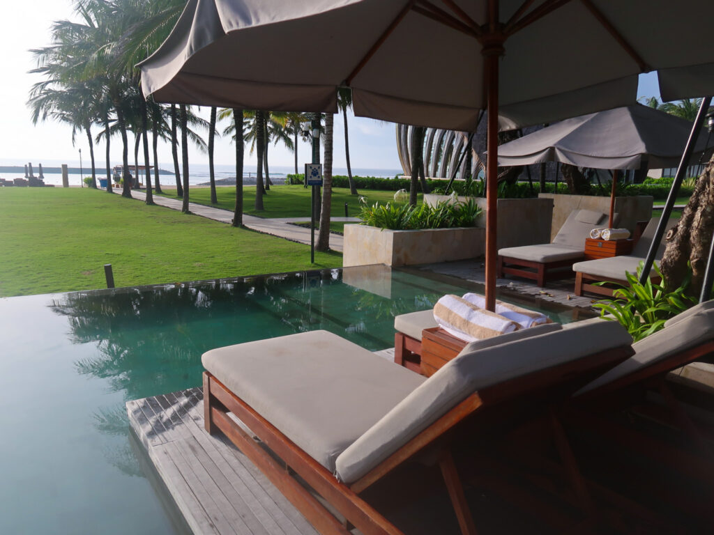 Sunlounges overlooking infinity pool and grassed area at The Kempinski Bali