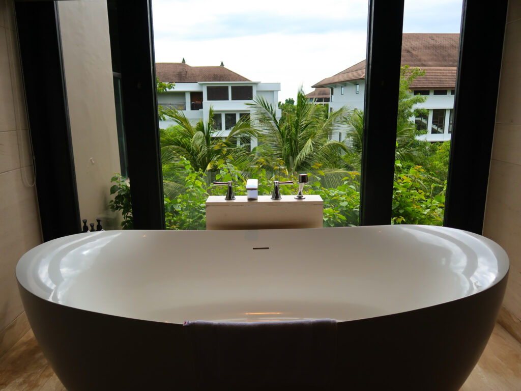 Freestanding bathtub overlooking tropical palm trees at The Kempinski